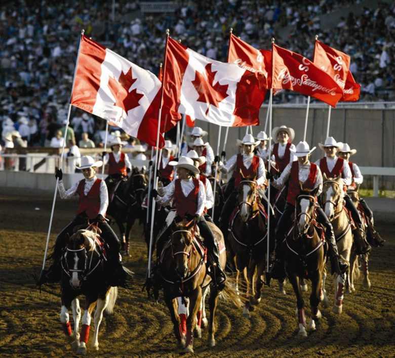 calgary stampede participants riding horses with canadian flags